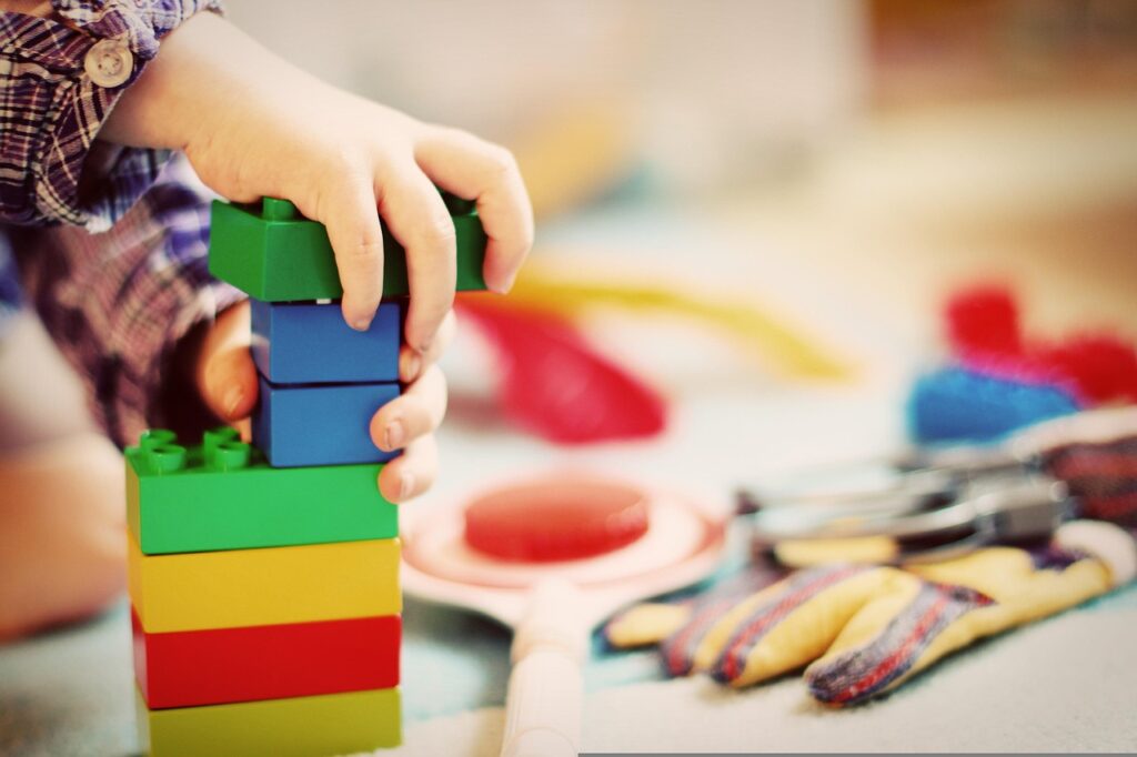 child building a colorful tower with toy blocks during playtime